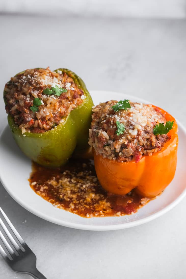 orange and green pepper on plate stuffed with meat, cheese, and green herb