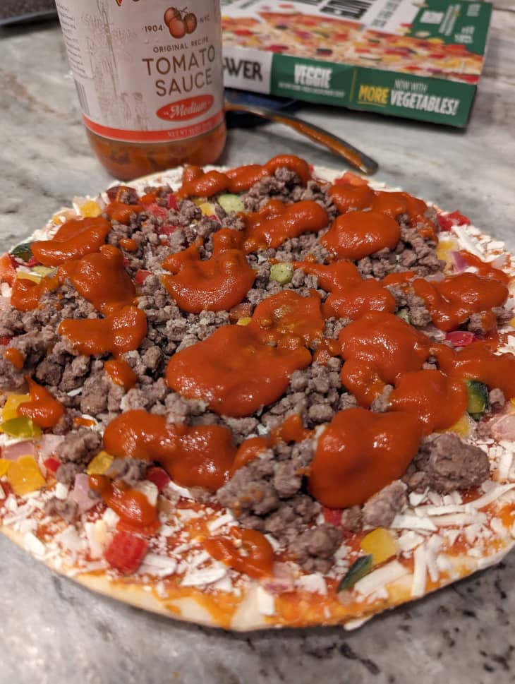 Tomato sauce on top of frozen pizza before baking.
