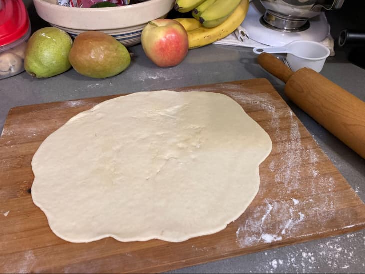 Jiffy pizza dough rolled out on wooden cutting board.