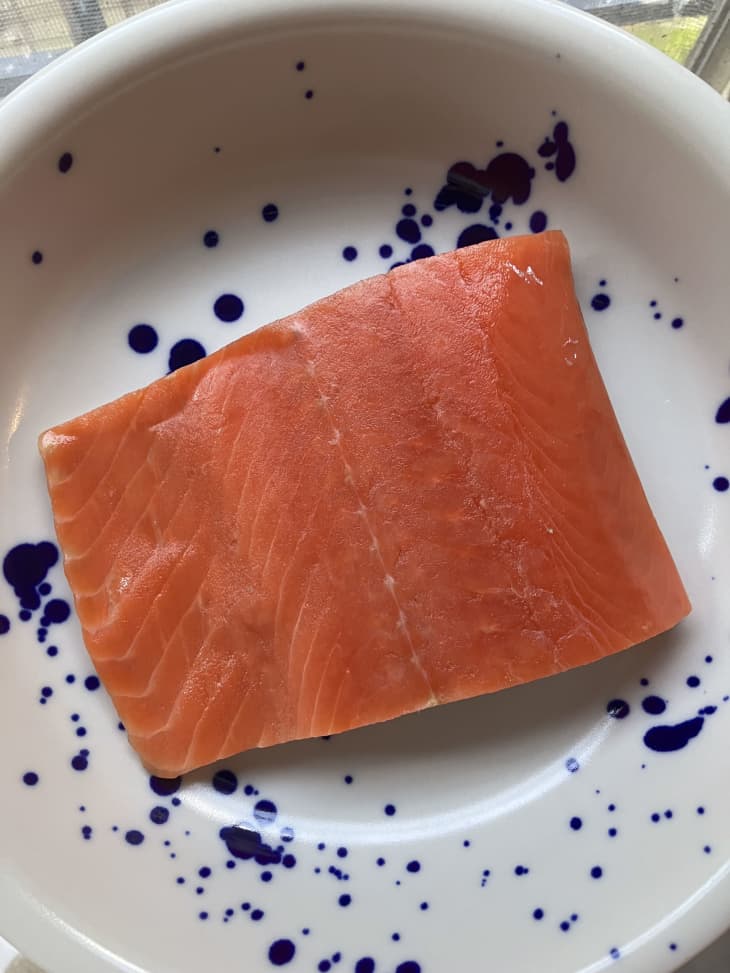 Uncooked salmon on a blue and white plate.