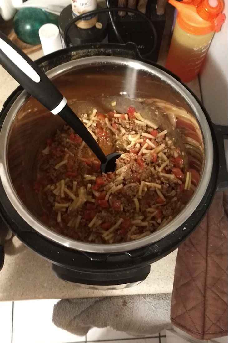 Crock pot full of ingredients including pasta and meat.