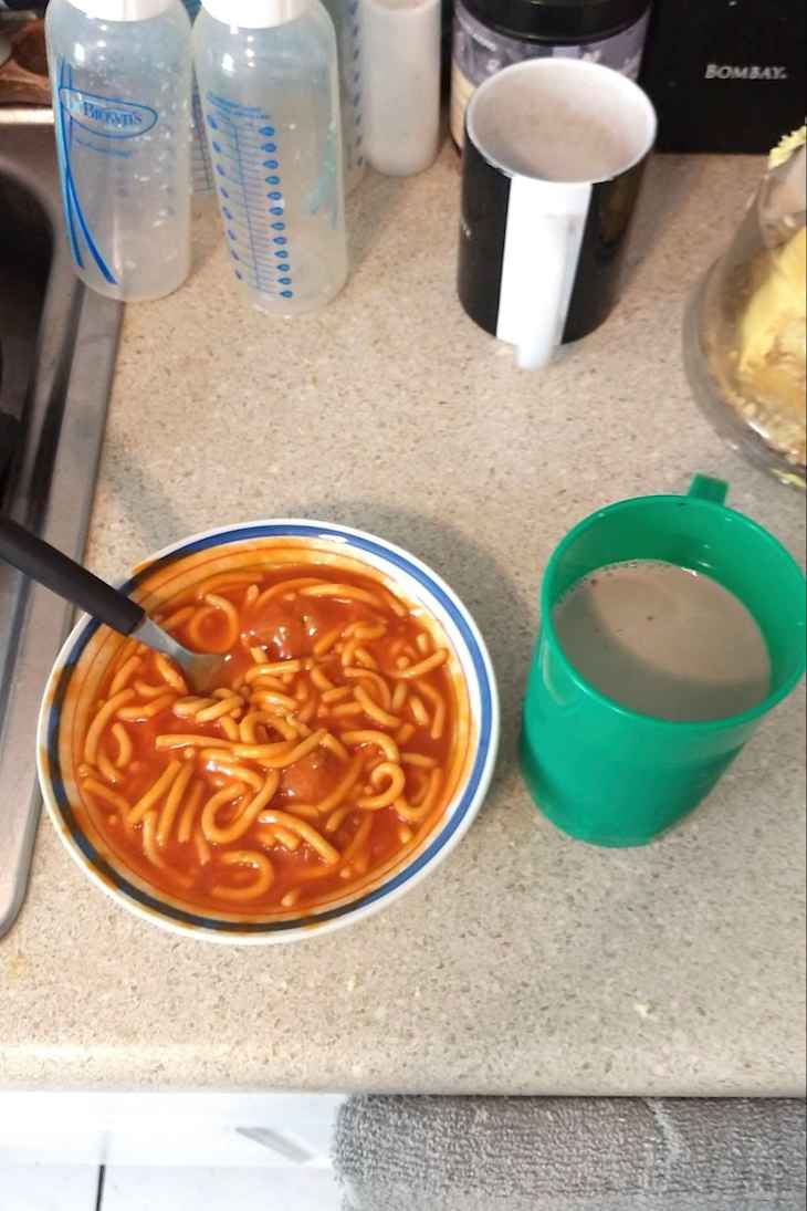 Spaghetti next to a drink in a green cup.