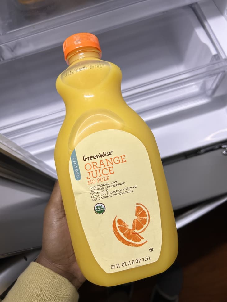 Someone holding Greenwise Orange Juice.