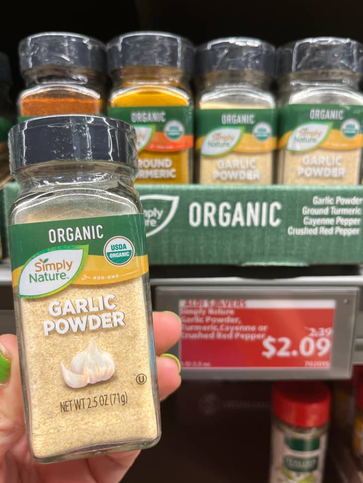 Someone holding garlic powder spice jar in Aldi supermarket.