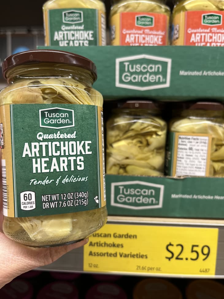 Someone holding container of artichoke hearts