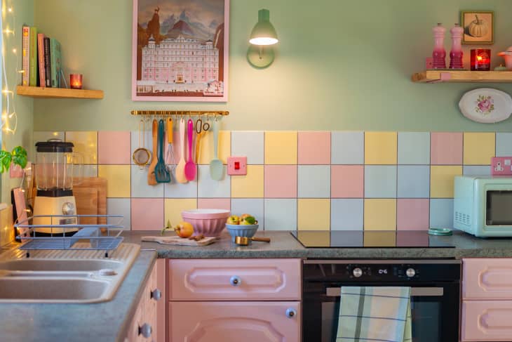 Pastel green wall with pastel tiling in kitchen with pastel pink cabinetry and pastel accessories.