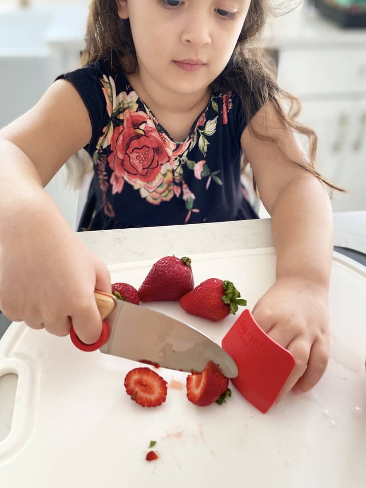 Little girl slicing strawberries