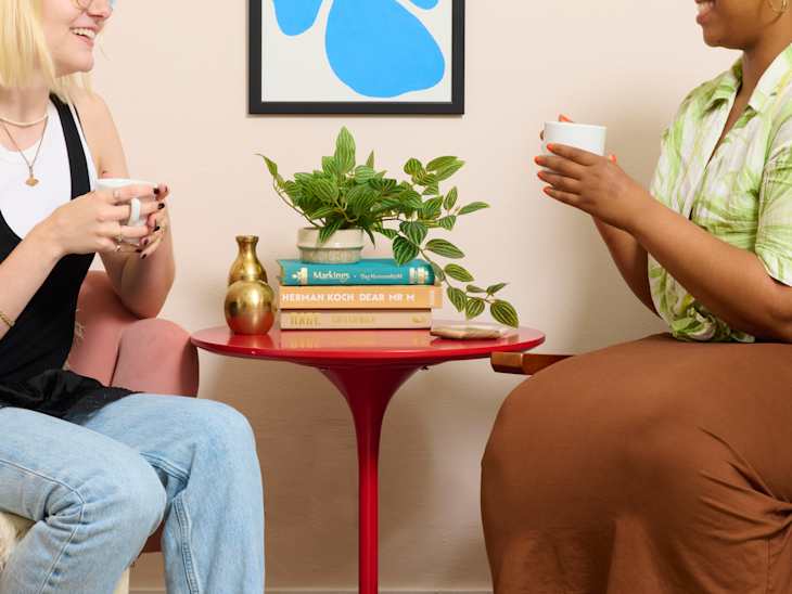 head on shot of two people holding cups of coffee and chatting