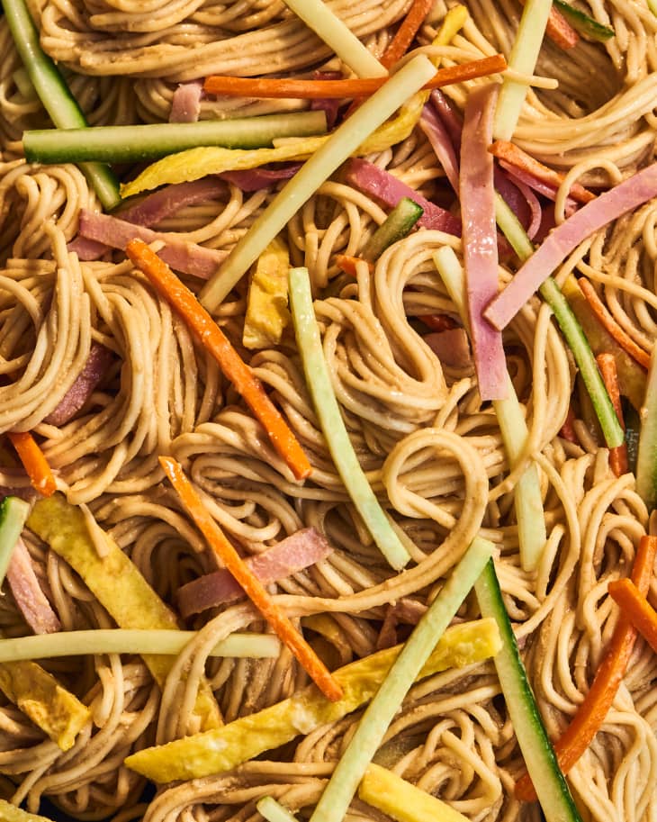 Close up photo of noodles with julienned vegetables, meat, dressing