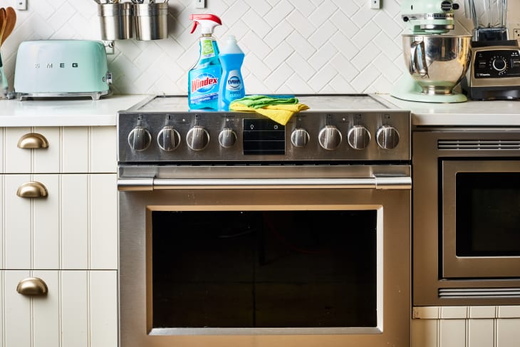 An oven inside a kitchen with cleaning products nearby
