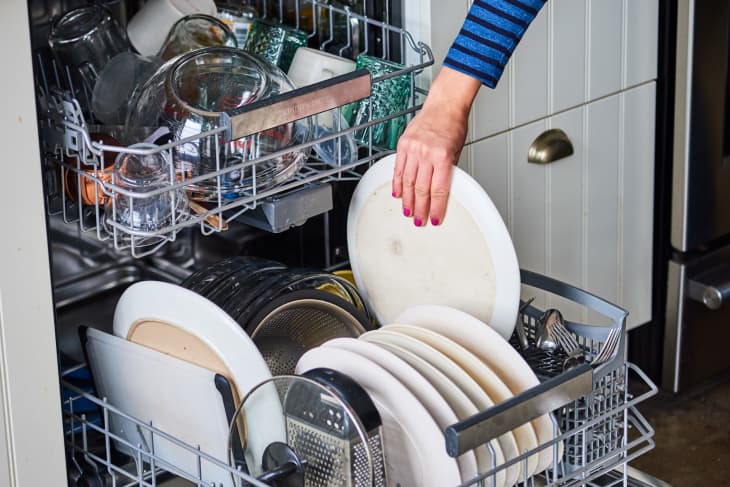 A person loading dishes into a dishwasher