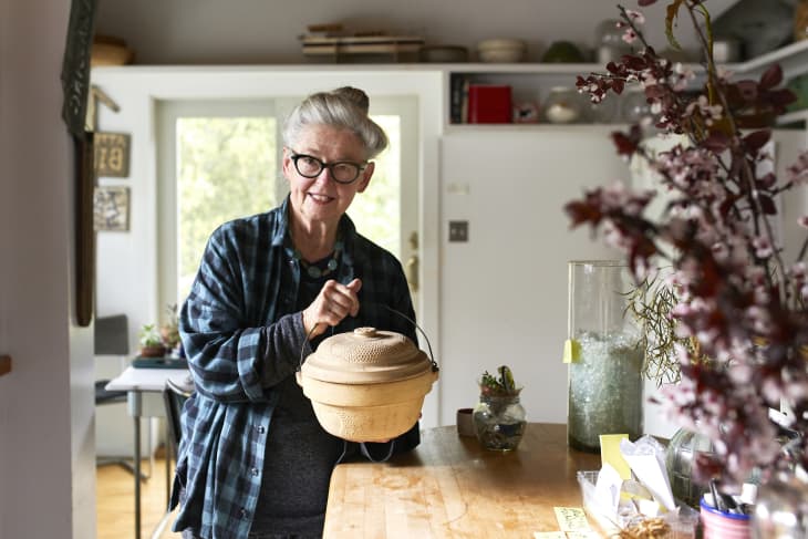 Joan stands in her kitchen and holds her clay pot