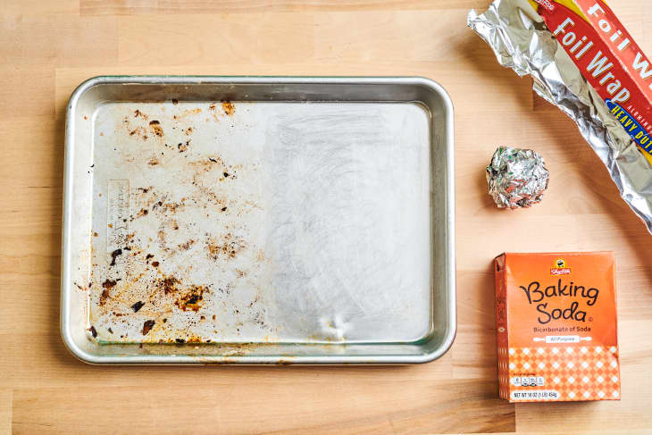 half cleaned baking sheet with a ball of aluminum foil and baking soda