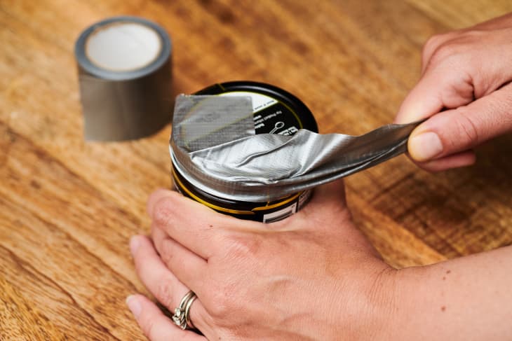 pulling on a piece of duct tape attached to top of a jar