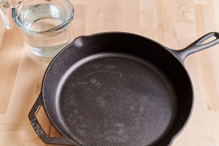 Cleaned cast iron skillet with a measuring cup filled with hot water