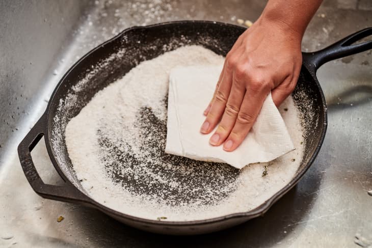 rubbing a paper towel into a cast iron skillet filled with kosher salt