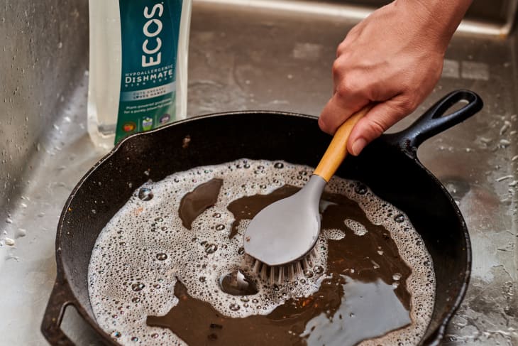 cleaning cast iron skillet with eco-friendly dish soap and scrub brush and water