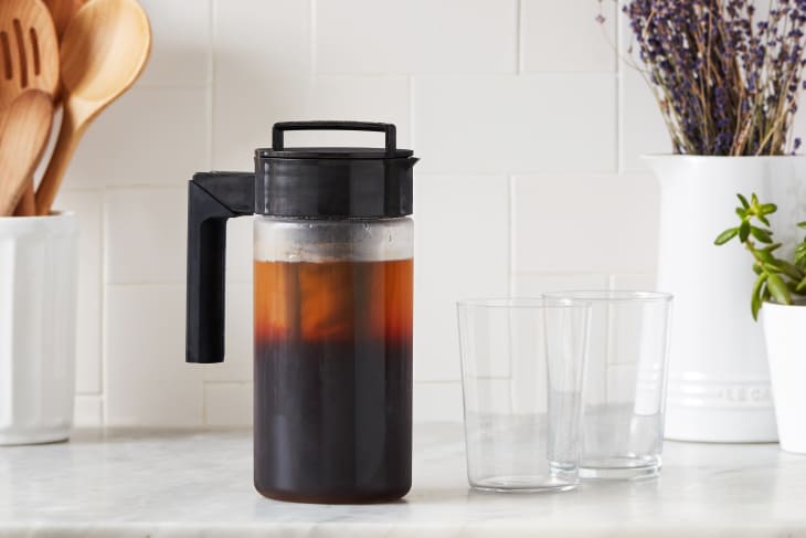 Takeya cold brew on countertop with two glasses on side.