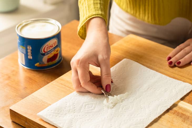 Someone dips key into Crisco on paper towel.
