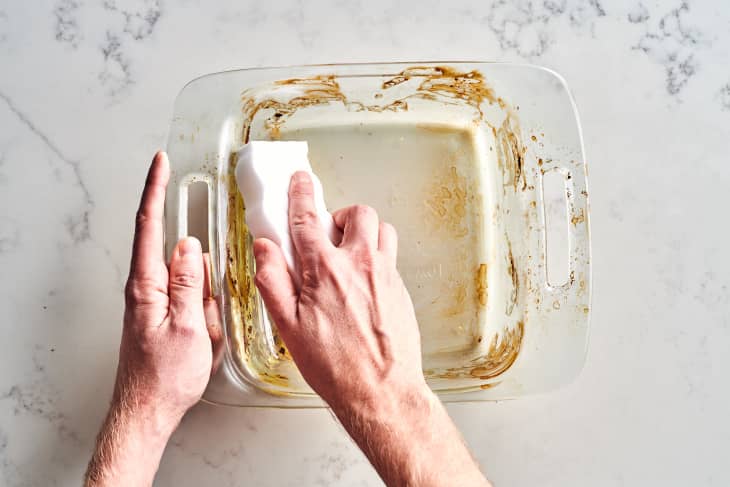 Hand cleaning glass bakeware with a magic erase sponge.