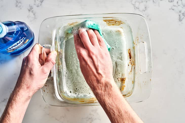 Hand cleaning glass bakeware with dawn soap.