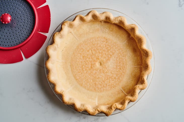 pie crust in tin sits next to a single pie weight