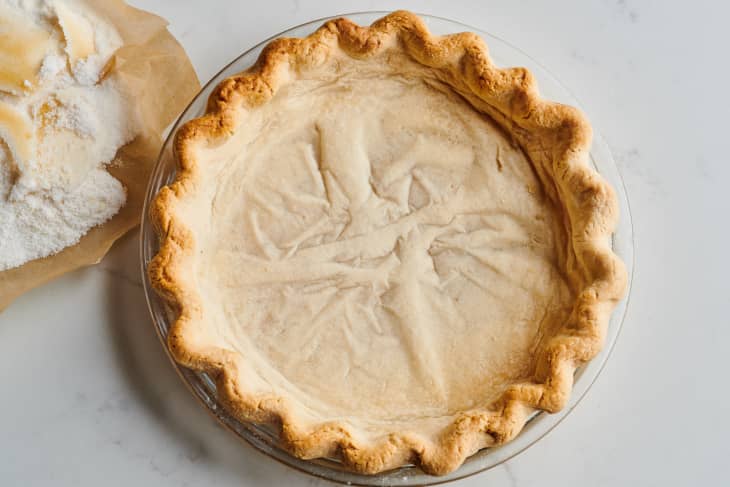 pie crust in tin sits next to a bag of sugar