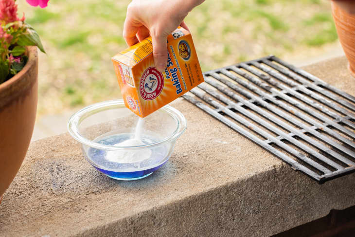 Someone pouring baking soda into bowl of dish detergent.