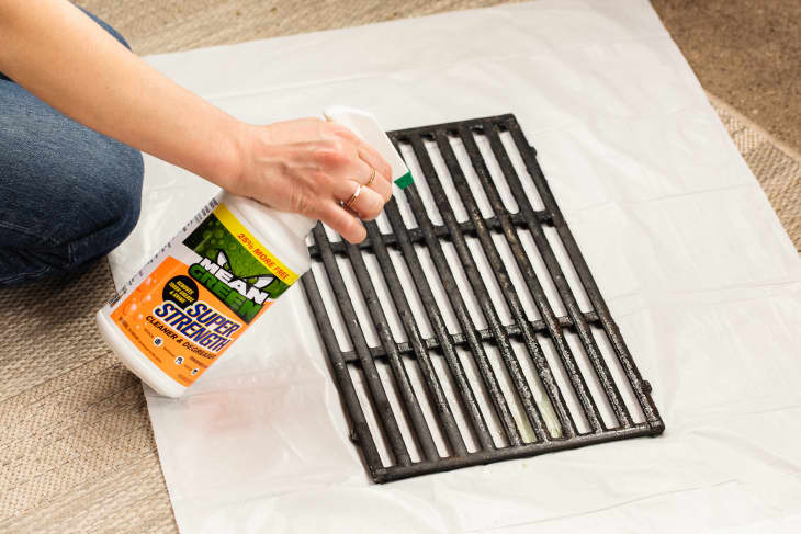 Someone spraying cleaning product onto grill grate.