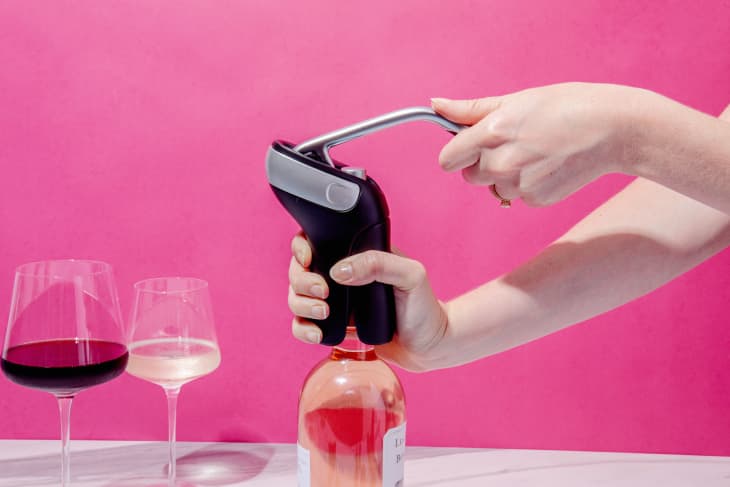 Someone using OXO SteeL Vertical Lever Corkscrew to open bottle of wine.