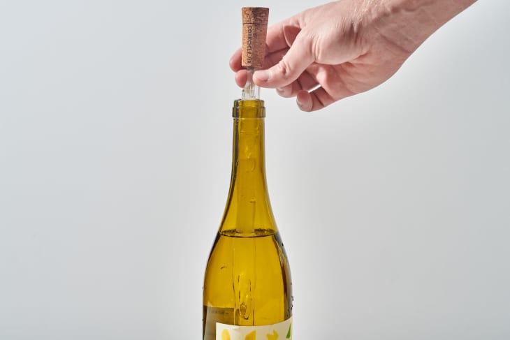 someone placing corkcicle in wine bottle