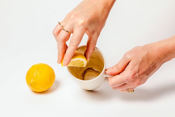Cleaning inside of stained coffee mug with lemon.