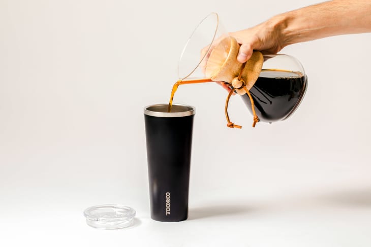 Someone pouring coffee into travel mug