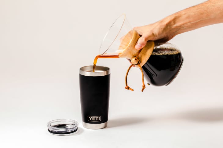 Someone pouring coffee into travel mug