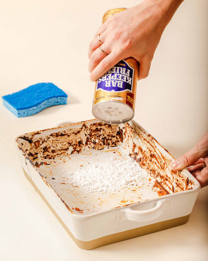 Someone sprinkling Bar Keepers Friend into baking dish.