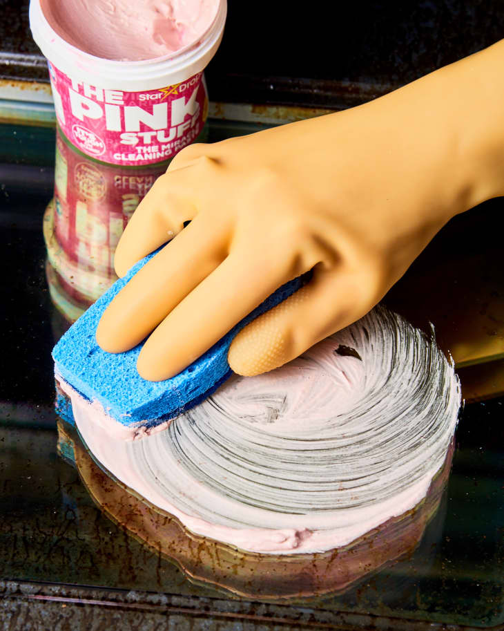 picture of a hand using pink stuff to clean inside of oven