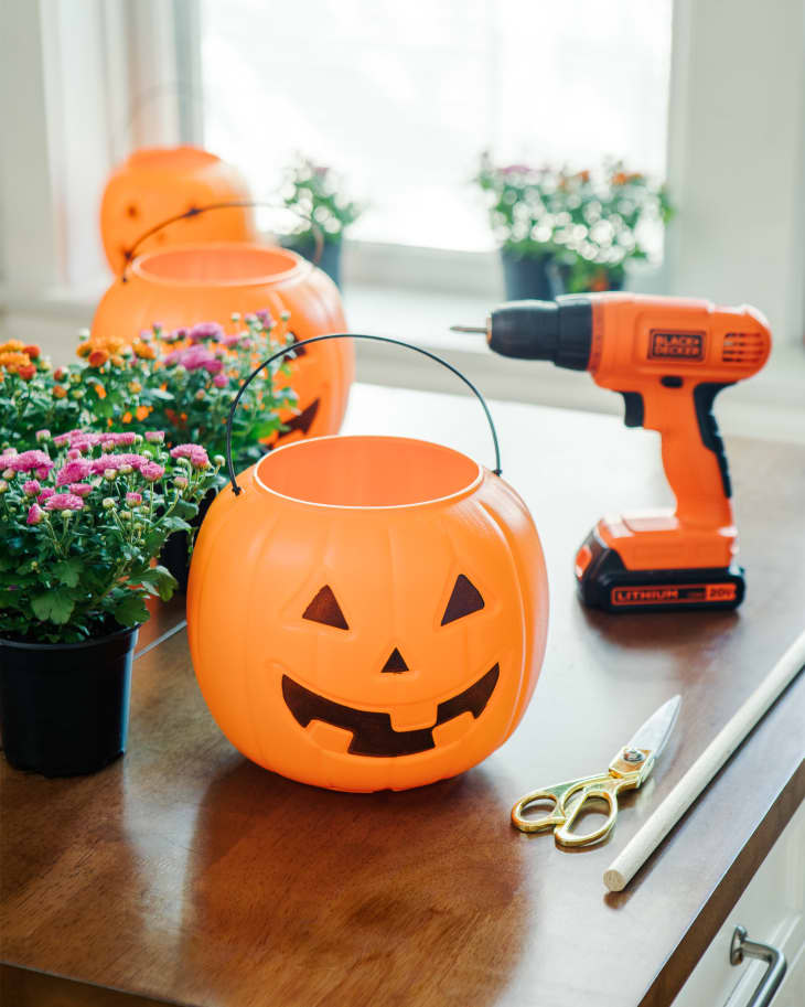 all of the supplies to make front porch halloween sculpture including; Plastic jack-o-lanterns, dowel, drill, flowers, and scissors.