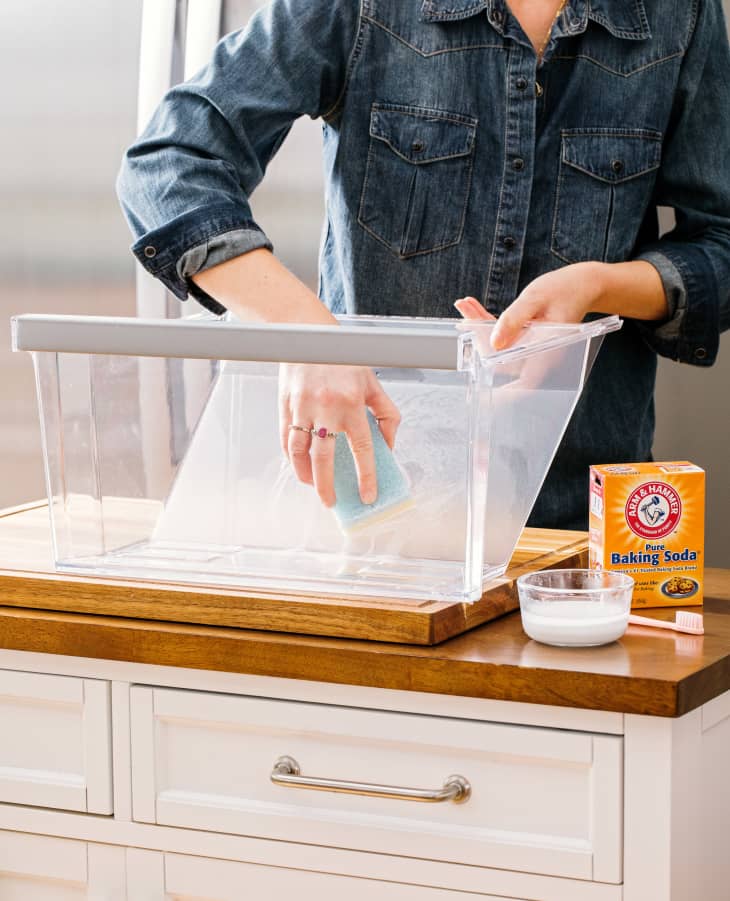 Someone cleaning refrigerator crisper drawer with baking soda method