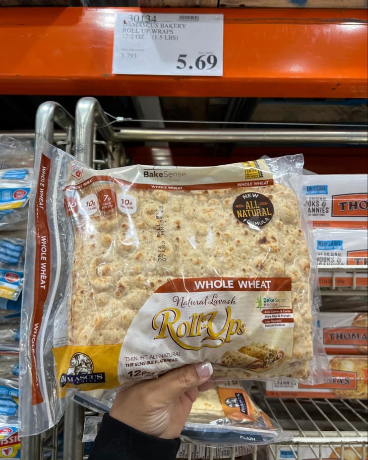 Someone holding up a package of Damascus Bakery Whole Wheat Roll-Ups in Costco store