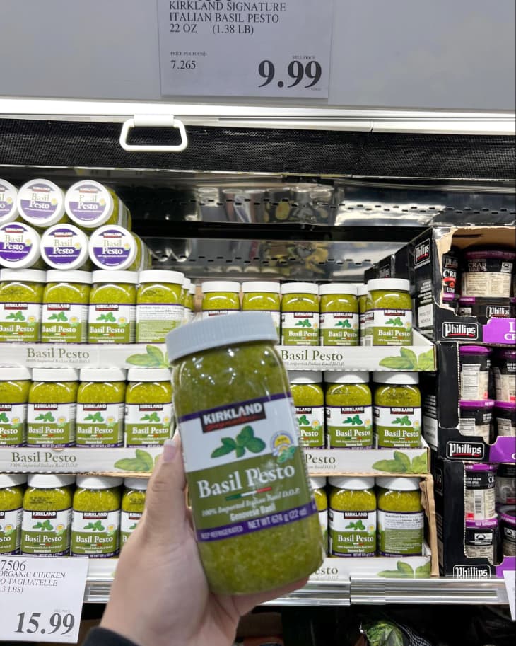 Someone holding up a package of Kirkland Signature Basil Pesto in Costco store