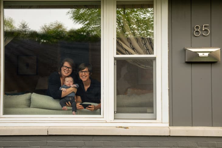 Robin holds newborn baby, Eliot, while she and Jodi smile from their window.