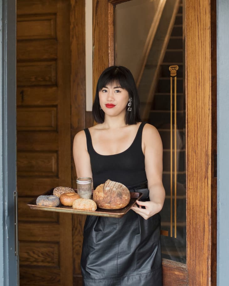 vicki tran walking outside her apartment with a tray full of baked bread and bagels