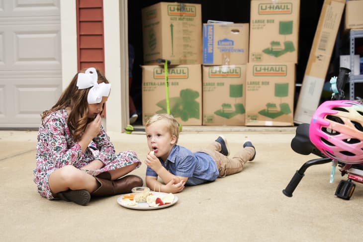 Little boy and girl eating snacks in the driveway
