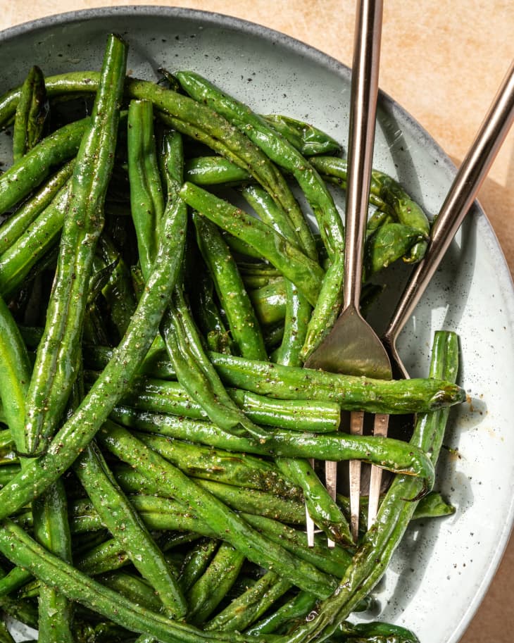A closeup of air Fryer Green Beans on a plate with some cutlery on the plate.