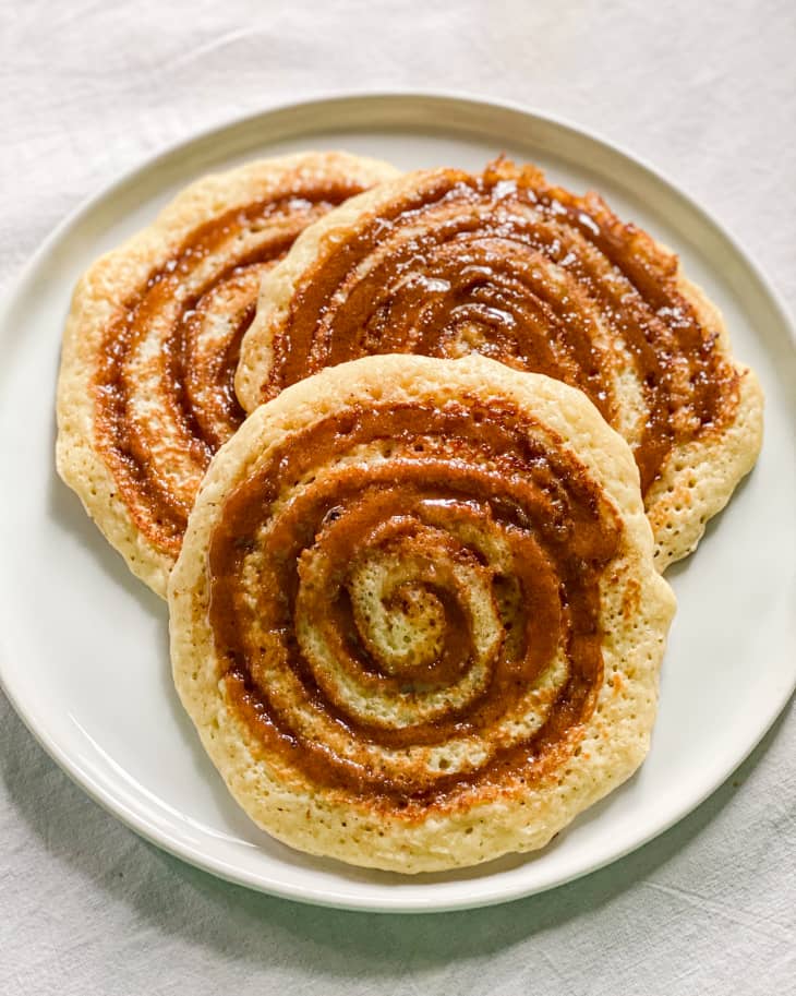 Three cinnamon roll pancakes on a white plate