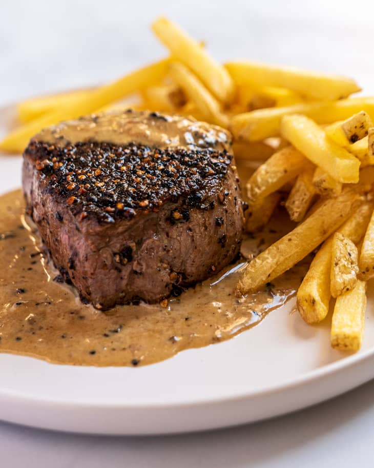 Steak Au Poivre on a plate with brown sauce, and french fries
