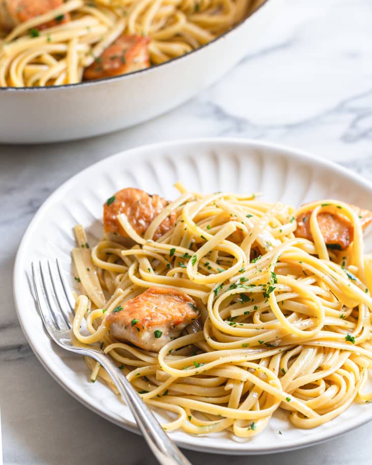 Chicken Scampi with linguini on a plate, with a fork on the plate, and a platter with more Chicken Scampi  behind it