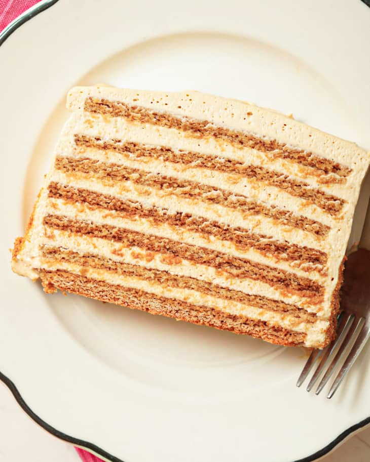 A slice of Honey cake (a layered cake with notes of honey and caramel) on a white plate, with a fork on the right.