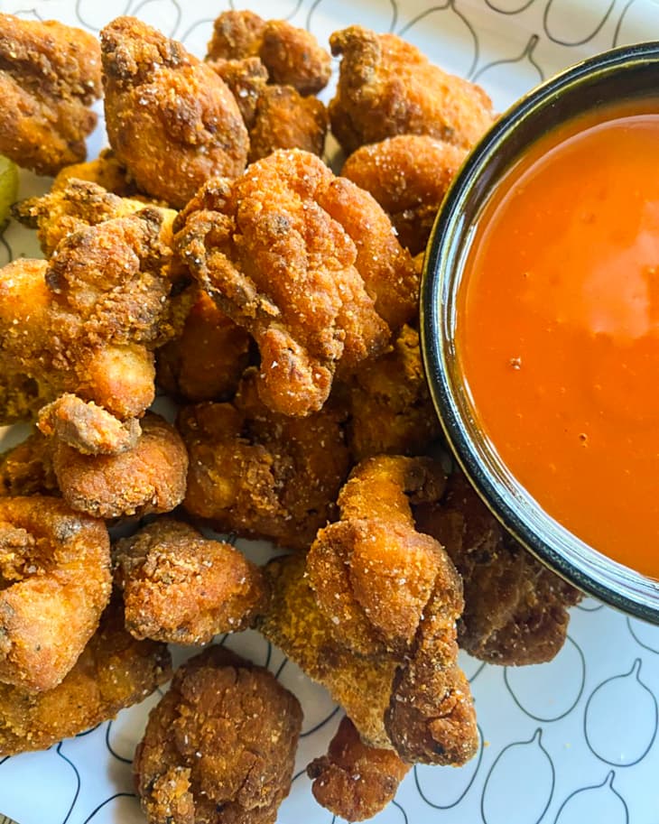 popcorn chicken (small pieces of fried chicken) on a tray with a ramekin of red sauce.