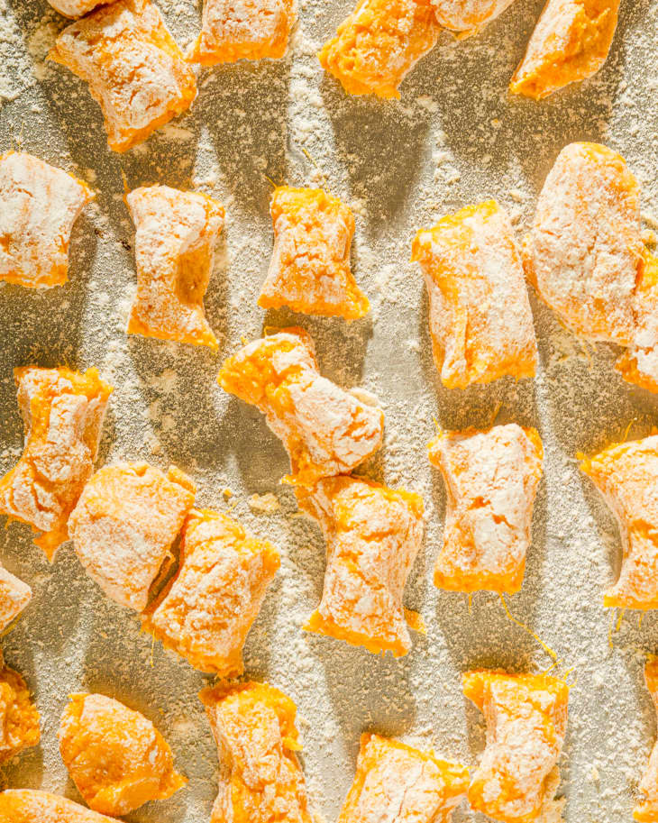 Sweet Potato Gnocchi uncooked, on a baking pan, with flour on top